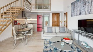 A modern apartment with a dining area, kitchen, living room, and a staircase leading to an upper level. - Fantastic Penthouse in Neos Marmaras (Sithonia)