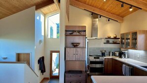 A modern kitchen with wooden cabinets, a central island, and built-in appliances.