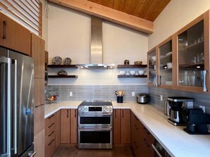 A modern kitchen with stainless steel appliances, wooden cabinets, and a tiled backsplash.
