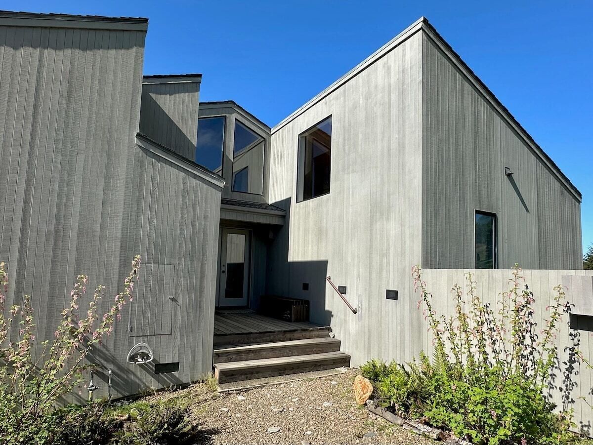 Un edificio moderno con fachada de concreto, una escalera que lleva a una puerta y un cielo despejado.