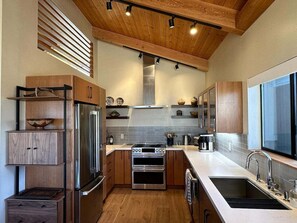 A modern kitchen with wooden cabinets, stainless steel appliances, and a large window.