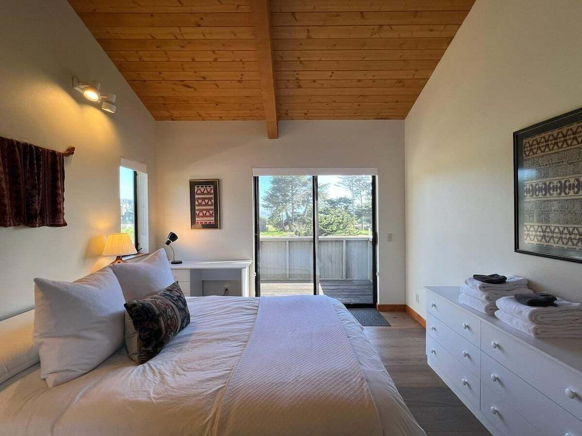 Une chambre à coucher avec un grand lit, un bureau et une vue sur l’extérieur grâce à une porte coulissante.