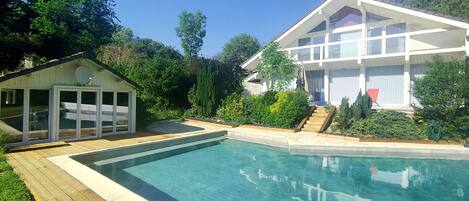 A modern house with a swimming pool, a covered patio, and a well-maintained garden.