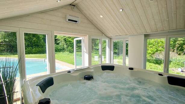 Un jacuzzi con vistas a una piscina y follaje exterior.