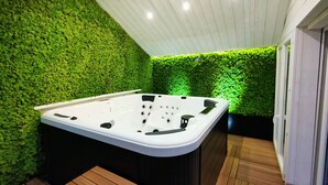Un área de spa con hidromasaje, suelo de madera y pared verde.