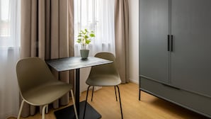 Una habitación moderna con una mesa de comedor, dos sillas, una planta en maceta y un amplio armario.