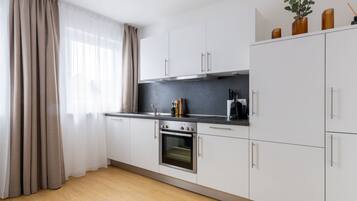 A modern kitchen with white cabinets, a built-in oven, and a black countertop.