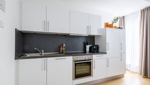 Una cocina moderna con armarios blancos, encimera negra y horno integrado.