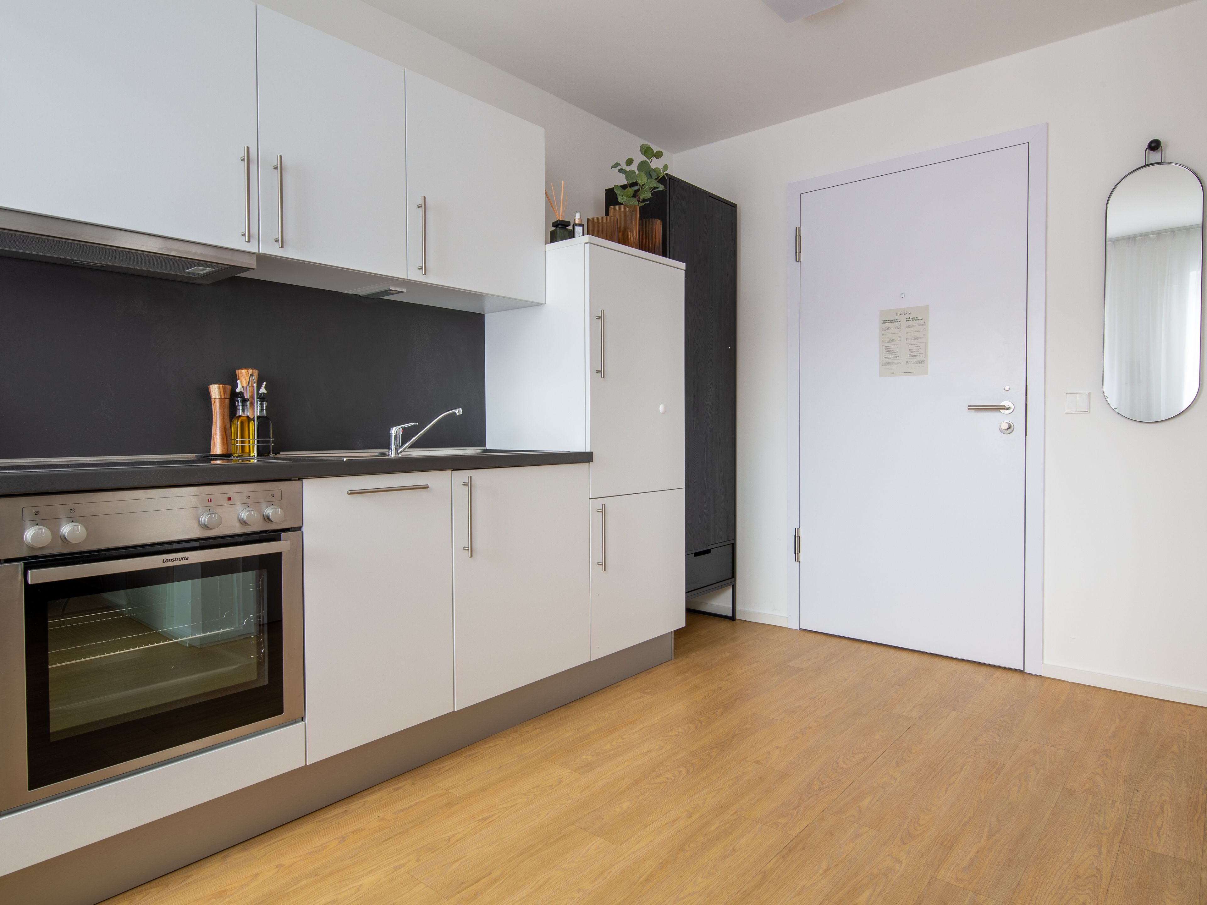 Una cucina moderna con mobili bianchi, un piano di lavoro nero e un forno integrato.