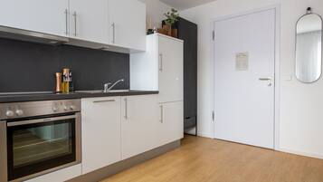 Una cucina moderna con mobili bianchi, un piano di lavoro nero e un forno integrato.