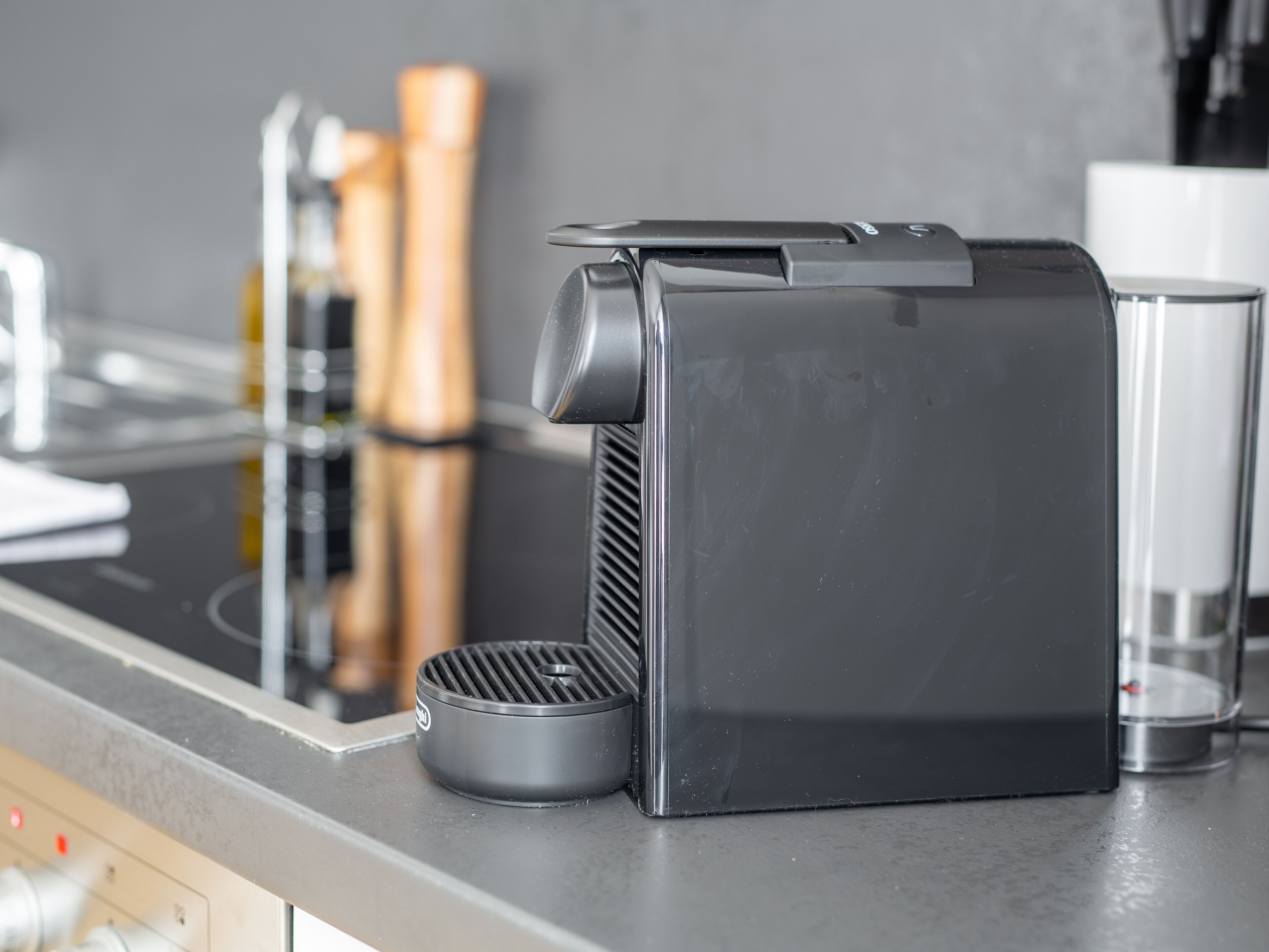 A kitchen with a coffee machine, a kettle, and a glass.