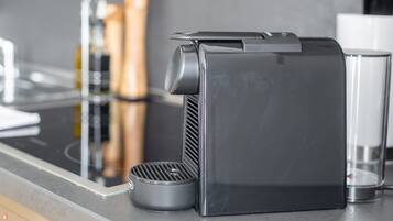 A kitchen with a coffee machine, a kettle, and a glass.