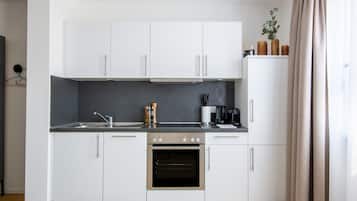 A modern kitchen with white cabinets, a black countertop, and an oven.