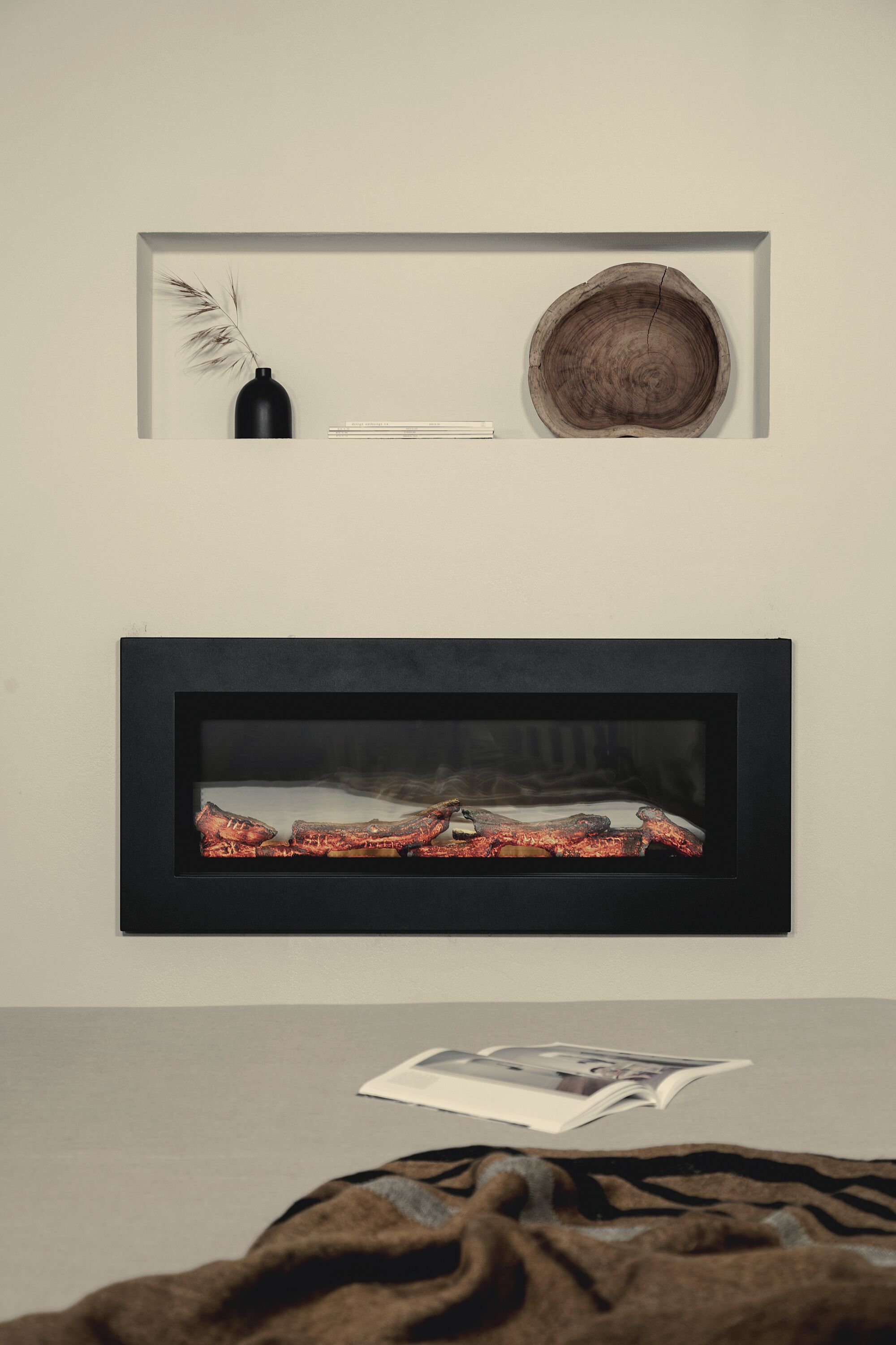 A framed photograph of a rustic wooden bowl and a black vase with a feather on a wall. Below, a framed picture of a red and black object is displayed.