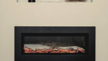 A framed photograph of a rustic wooden bowl and a black vase with a feather on a wall. Below, a framed picture of a red and black object is displayed.