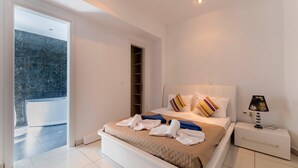 Een moderne slaapkamer met een groot bed, een nachtkastje, een lamp en een schuifdeur naar een balkon.