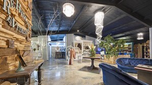 Eine geräumige Lobby mit hoher Decke, Holzwandverkleidung, einem blauen Sofa und hängenden Kristalllüstern.
