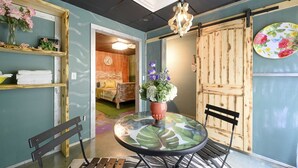 Ein gemütliches Zimmer mit einem Bett, einem Tisch mit Stühlen, einer Holztür und einem Regal mit Handtüchern.