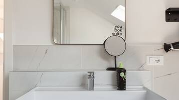 A bathroom with a white sink, a mirror, and a soap dispenser.