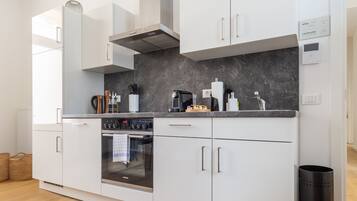 Una cocina moderna con armarios blancos, horno empotrado y campana extractora de acero inoxidable.