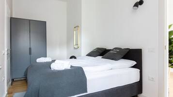 A modern bedroom with a large bed, grey bedding, and matching pillows.