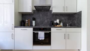 A modern kitchen with white cabinetry, a black countertop, and a Siemens oven.