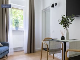 Quarto moderno e bem iluminado com uma mesa de jantar, cadeiras, um vaso de planta e vista para o verde lá fora.