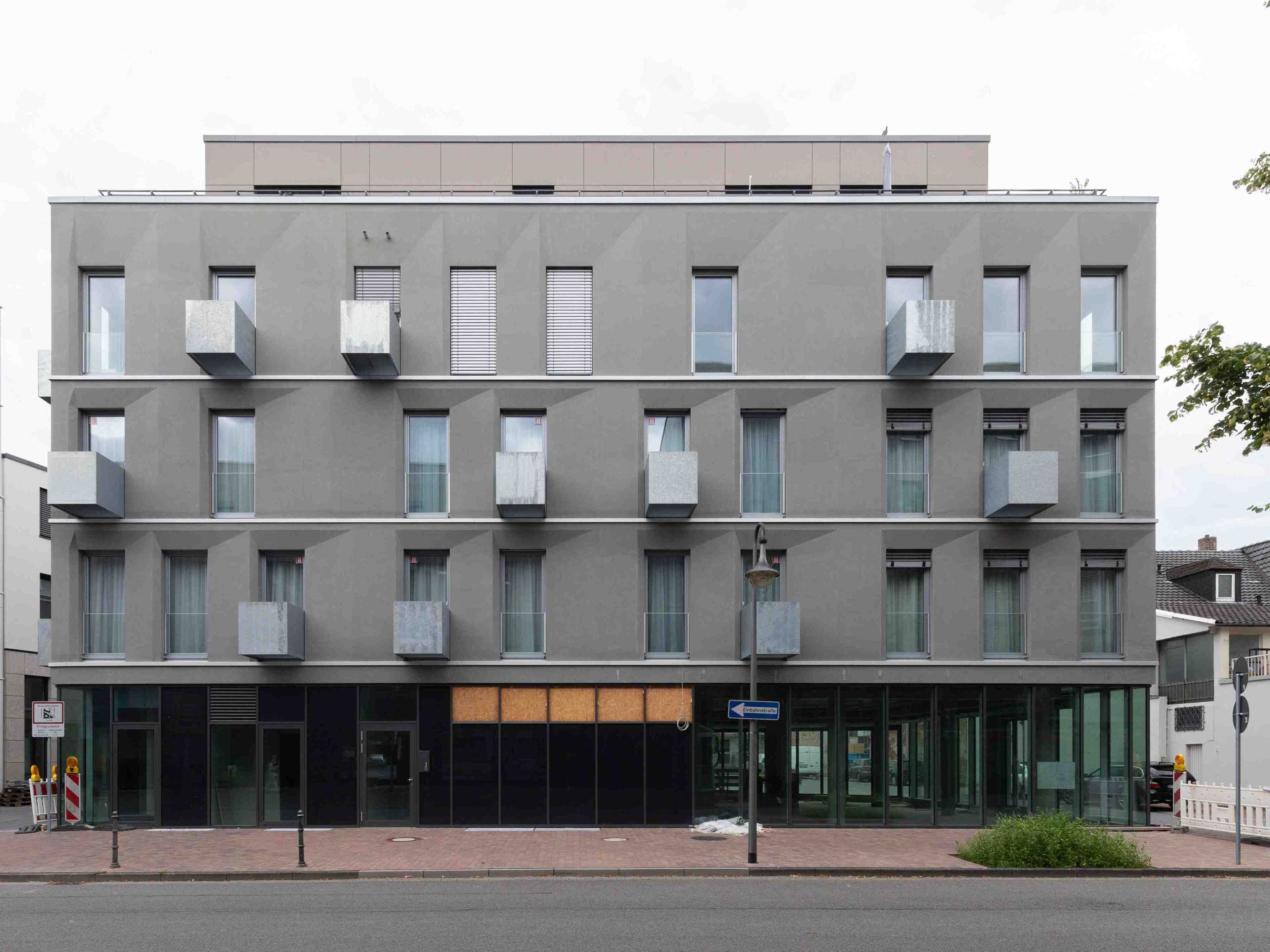 A modern multi-story building with a flat facade, large windows, and balconies.