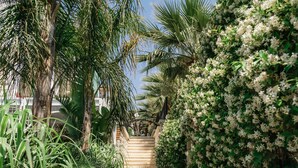 A pathway lined with lush greenery and flowering plants, leading to a staircase. - Monreve Alaçatı (Cesme)