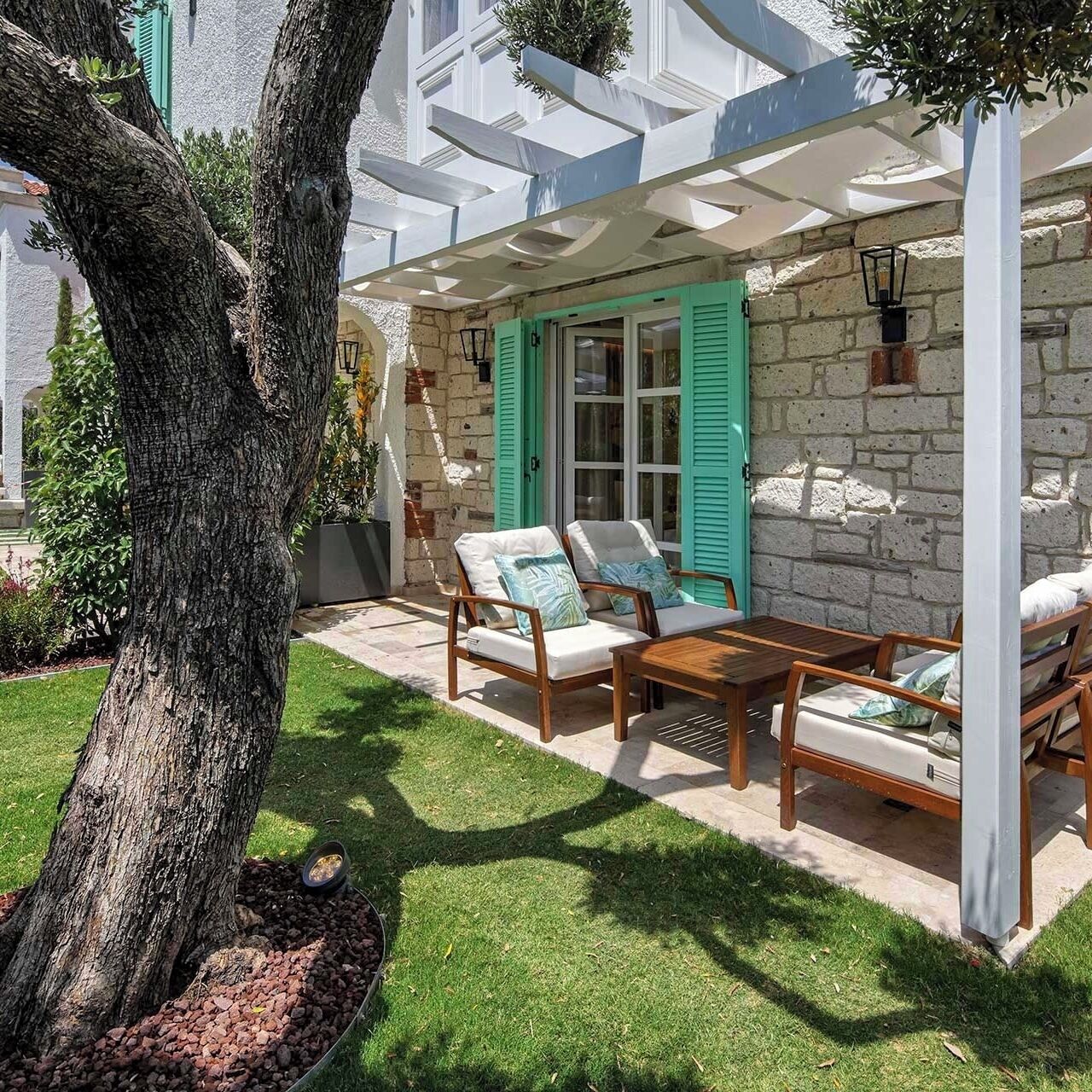 A patio with outdoor furniture, a tree, and a stone wall.