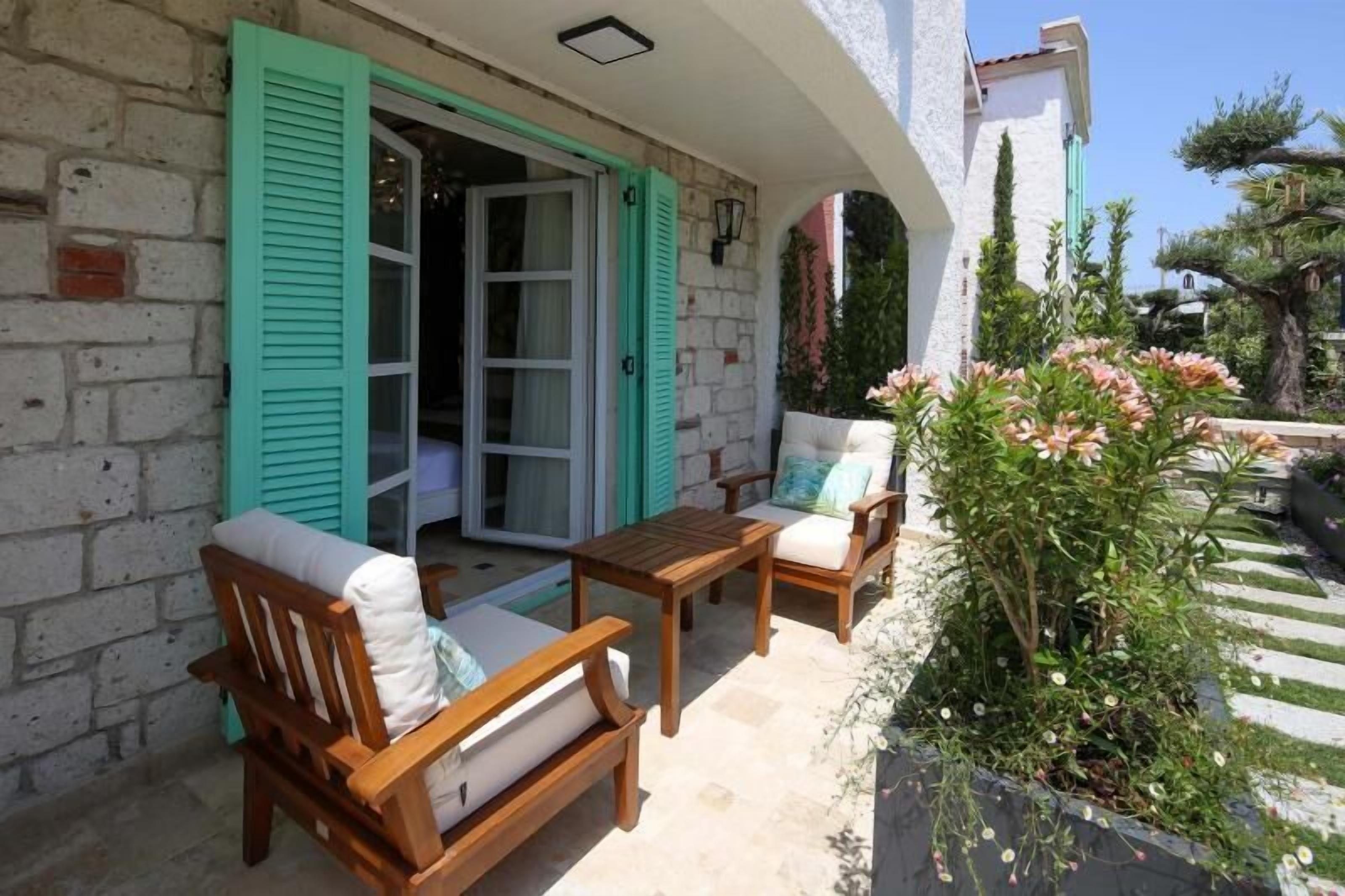 An outdoor seating area with wooden furniture and a stone wall.