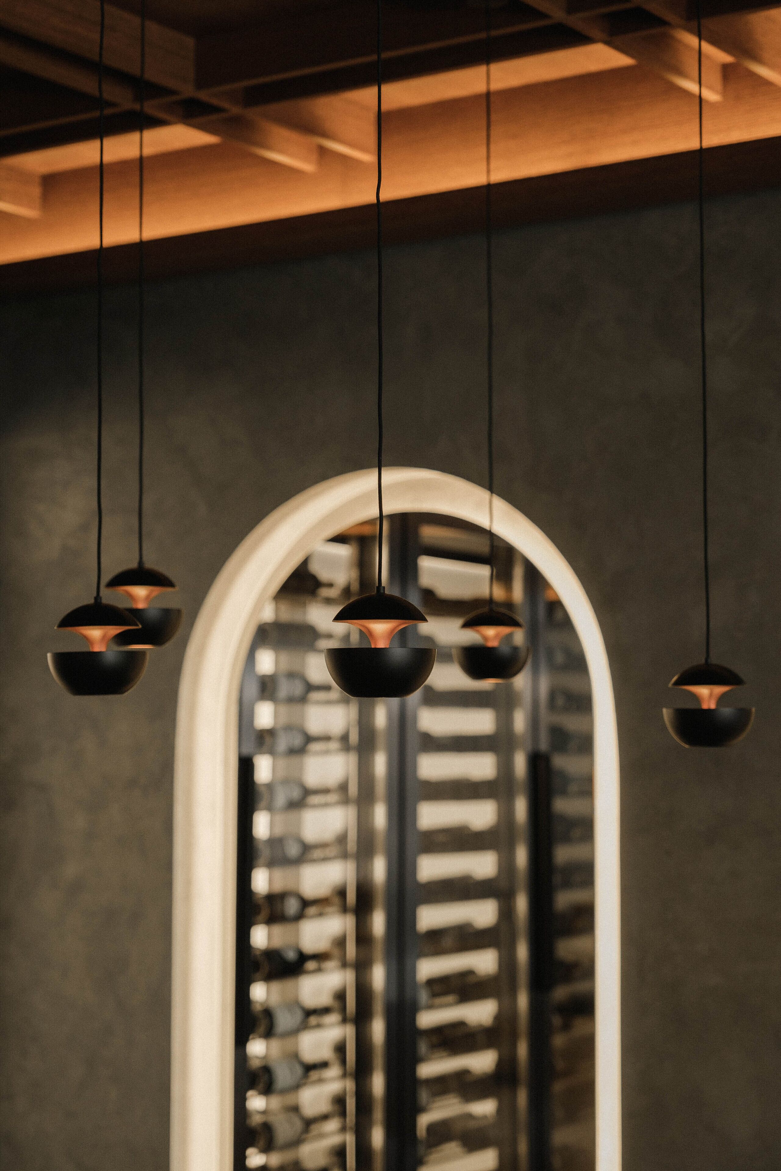 Un intérieur moderne agrémenté de luminaires suspendus et d’une grande fenêtre en arc de cercle.