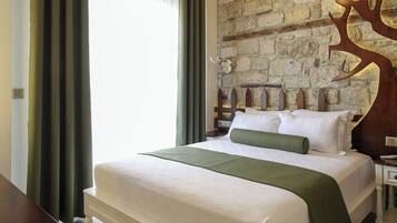 Un lit bien fait, agrémenté d’un plaid vert, avec un mur en briques et une tête de lit décorative en forme d’arbre.