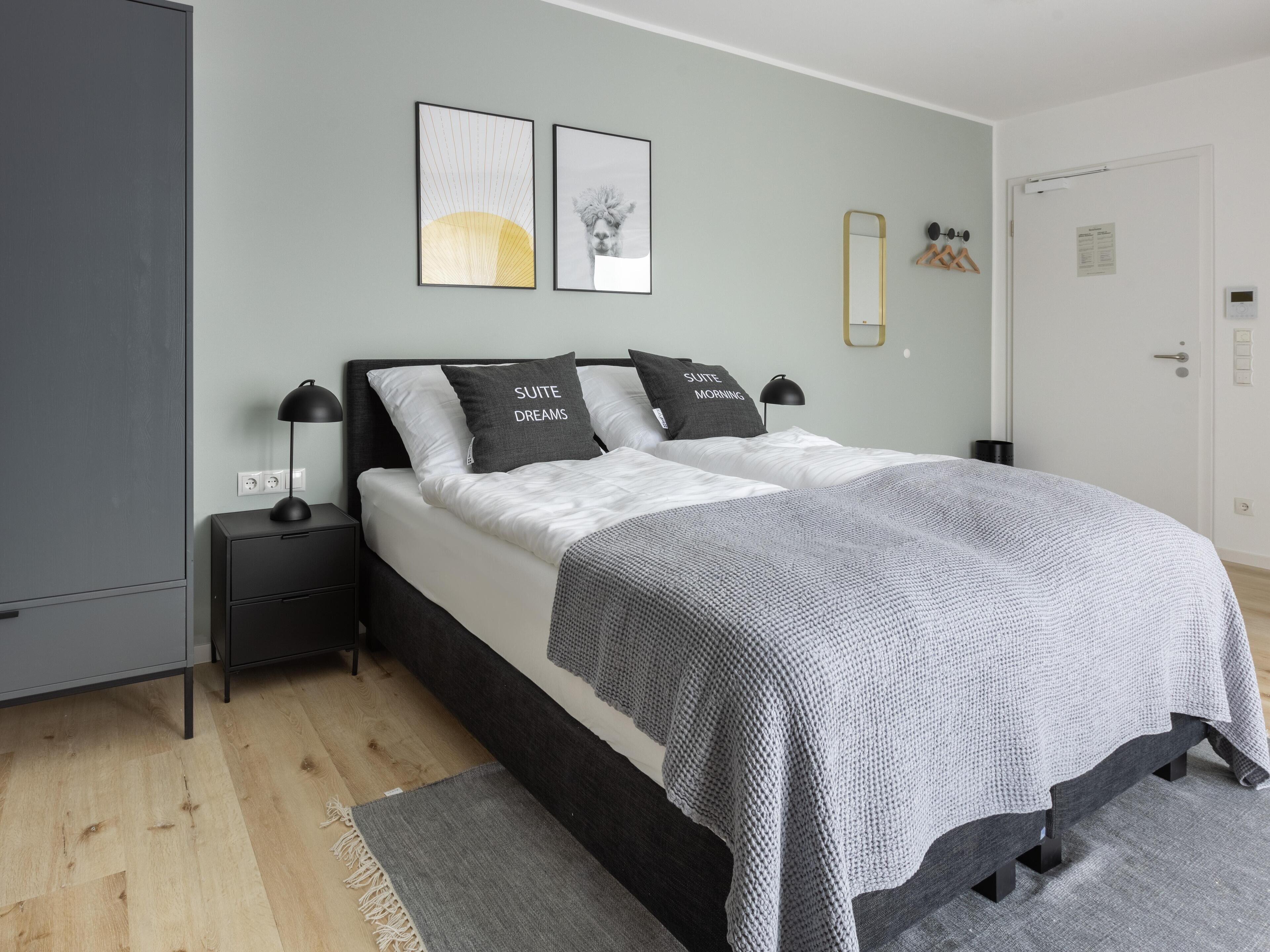 Un dormitorio moderno con cama, mesitas de noche, lámpara y obra de arte en la pared.