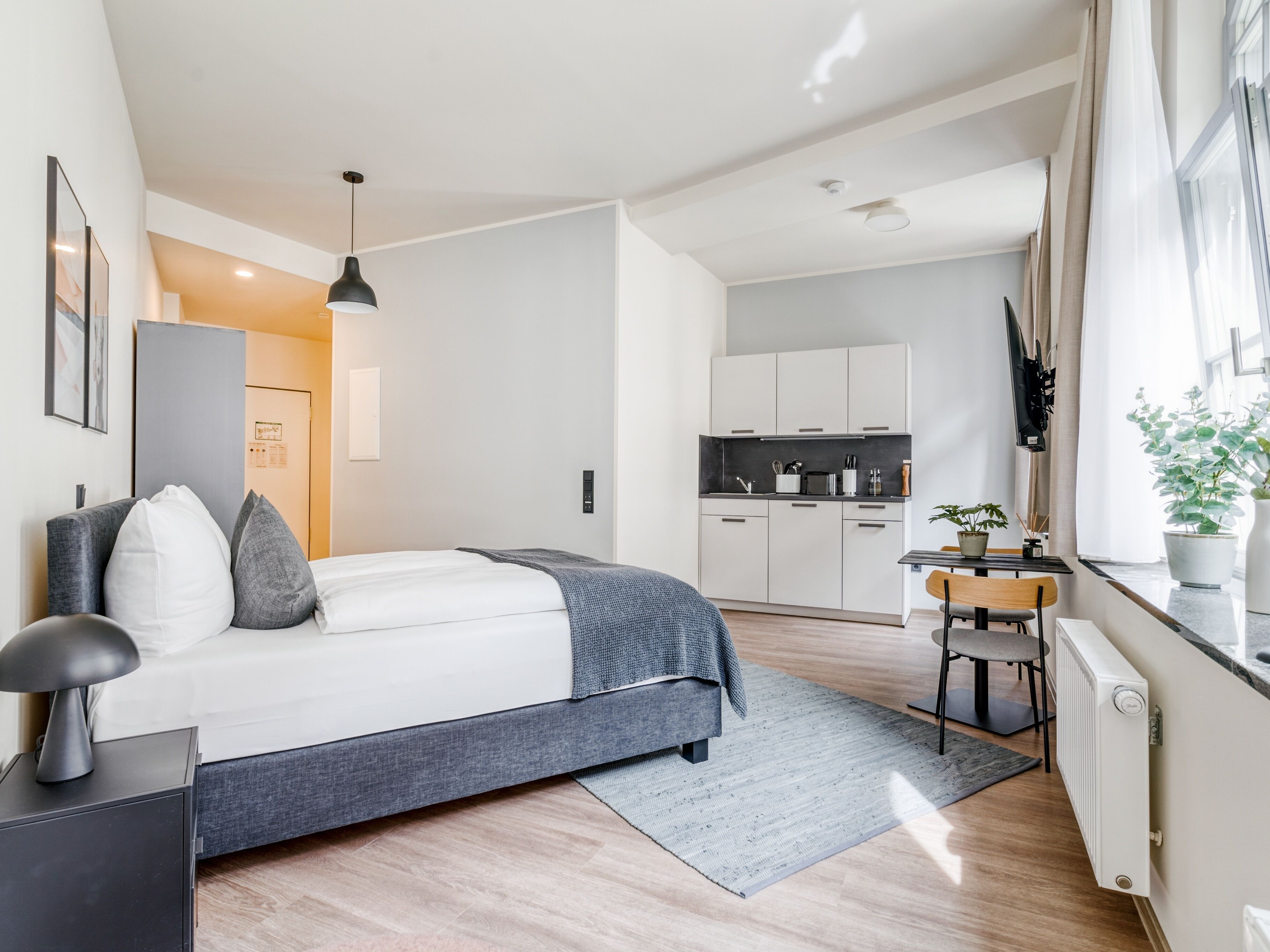 A modern bedroom with a bed, bedside table, and a desk with a chair.