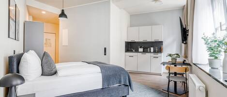 A modern bedroom with a bed, bedside table, and a desk with a chair.