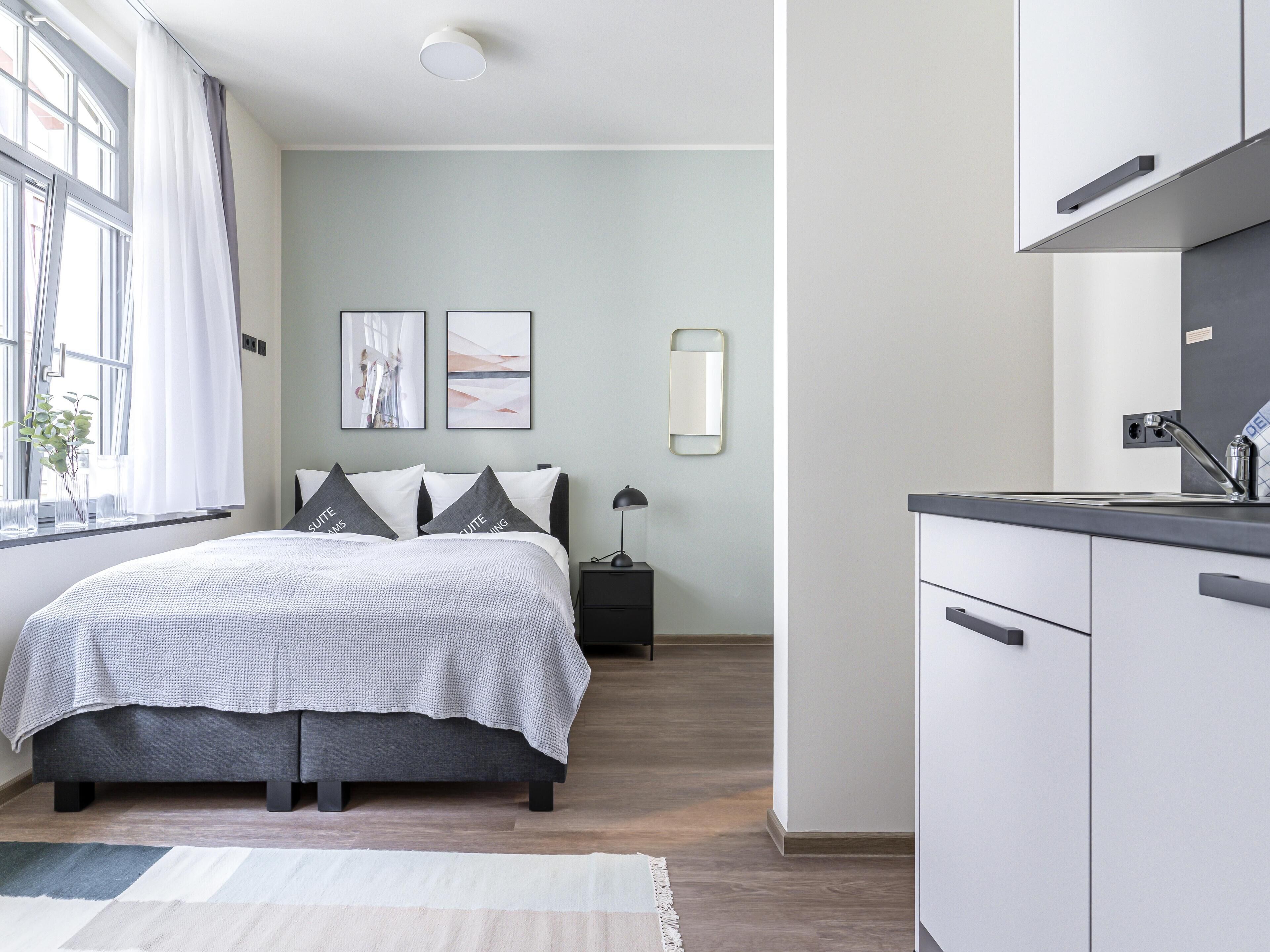 A modern bedroom with a bed, bedside tables, a nightstand, and a window with curtains.