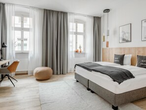 Een moderne hotelkamer met een groot bed, een bureau en een stoel.