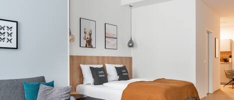 A modern bedroom with a bed, a grey sofa, a small table, and a bench.