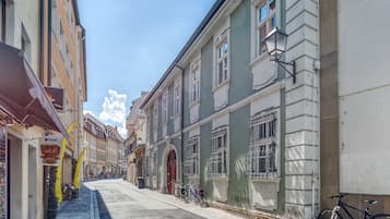 Una calle estrecha flanqueada por edificios históricos, una bicicleta estacionada en la acera y un cielo azul despejado.