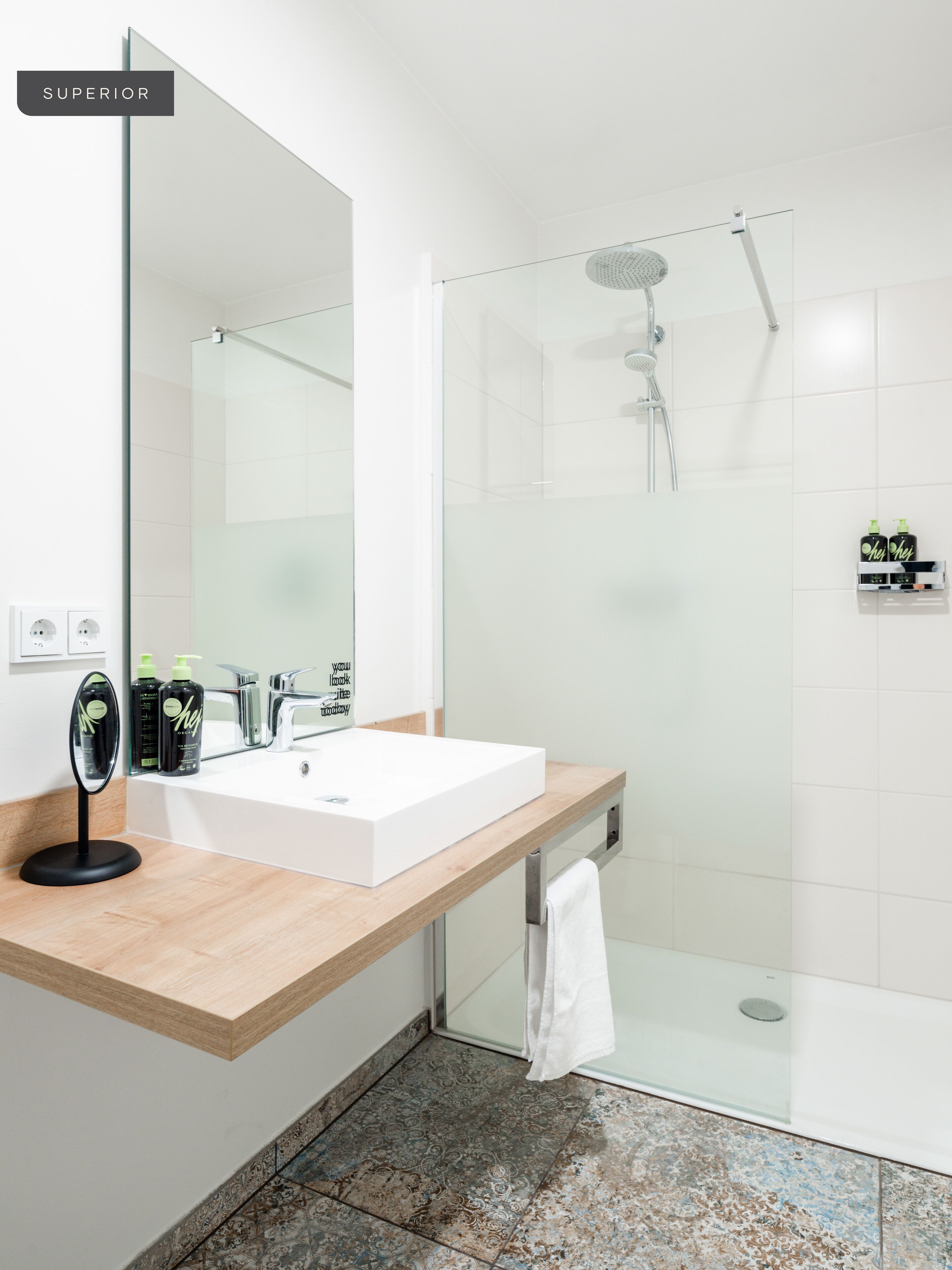 A modern bathroom with a white sink, a large mirror, and a glass-enclosed shower area.