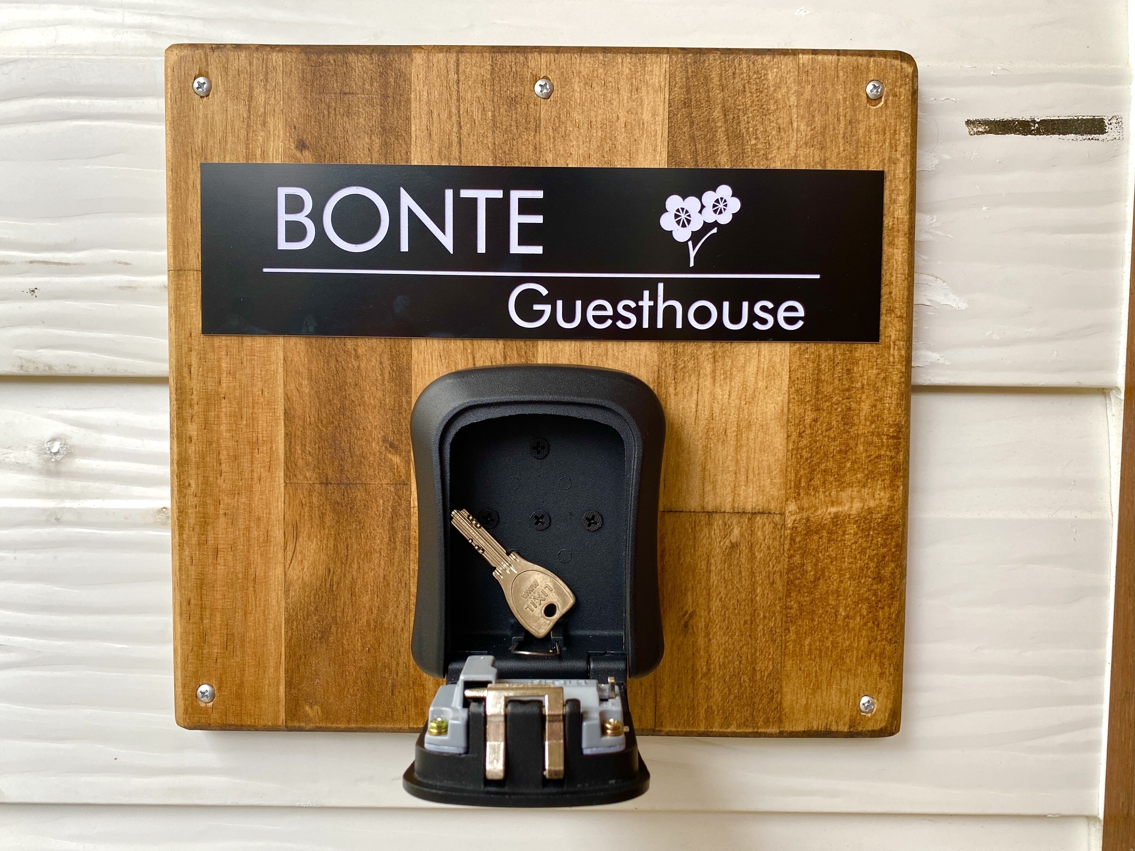 A wooden sign with 'BONTE Guesthouse' and a keyhole lock.