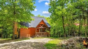 Une cabane en bois dotée d’un porche, entourée d’arbres et surplombant un ciel dégagé.