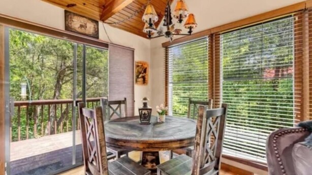 Une table ronde entourée de chaises, dans une pièce dotée de poutres en bois et de grandes fenêtres.
