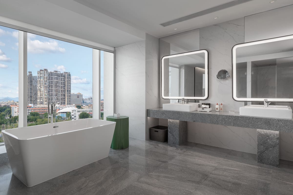 A modern bathroom with a freestanding bathtub, two sinks, and large mirrors.