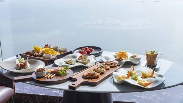 A table with various dishes and drinks, overlooking a body of water. - Crowne Plaza Xiamen Jimei by IHG (Xiamen)
