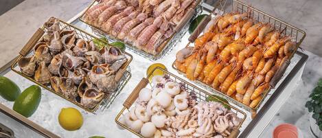 A seafood display with various types of shellfish and shrimp on ice, accompanied by lime wedges.