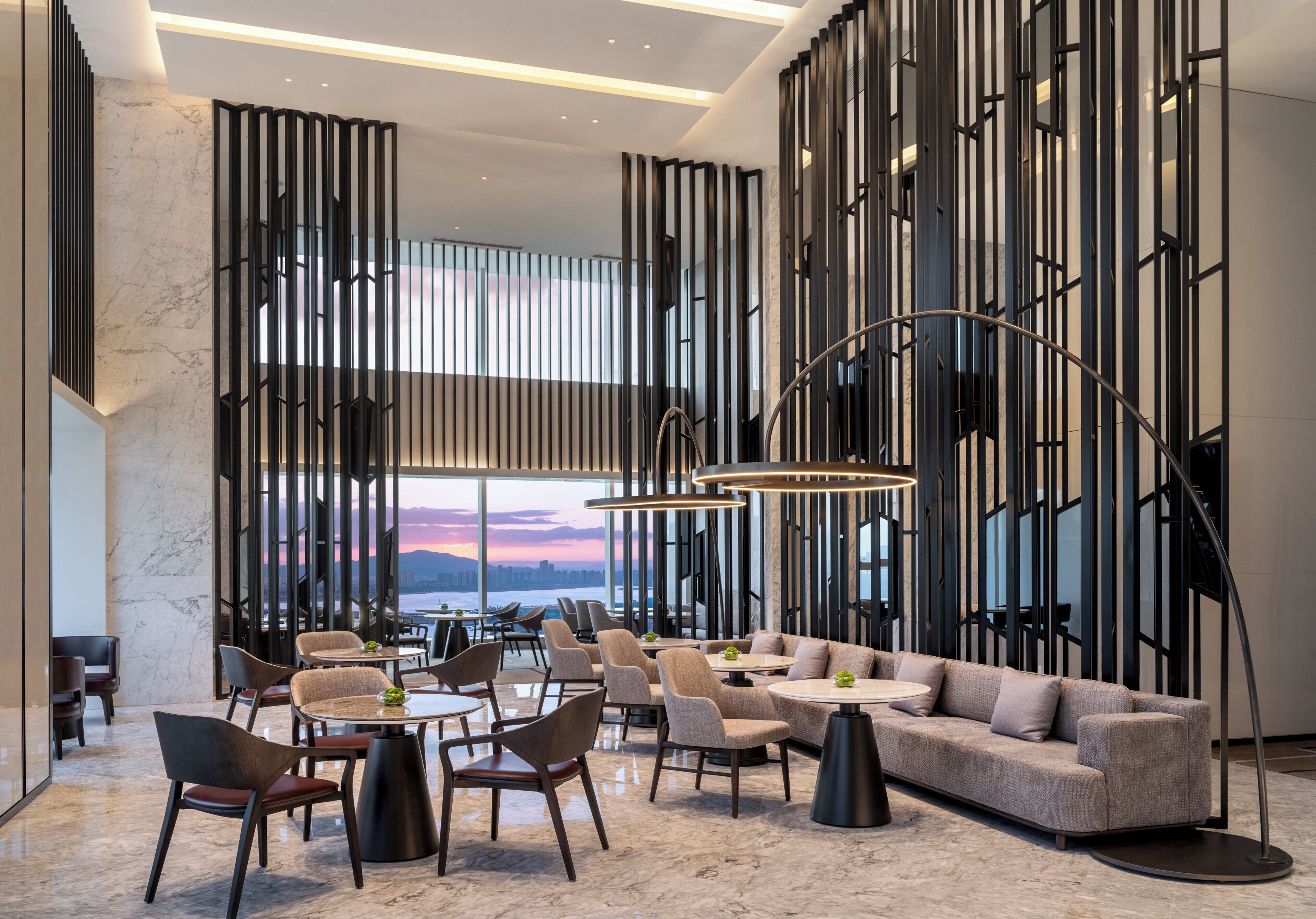 A modern interior with a seating area, tables, and a view of the cityscape.
