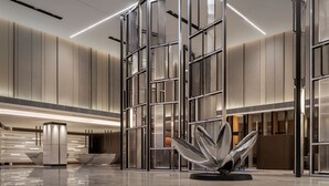 A modern lobby with a central glass partition, a reflective sculpture, and a sleek reception desk. - Crowne Plaza Xiamen Jimei by IHG (Xiamen)