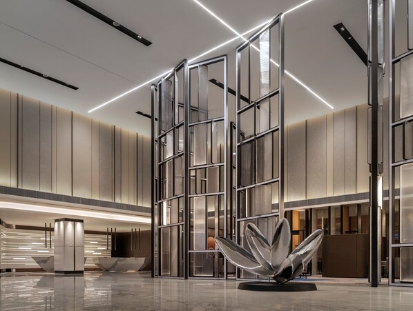 A modern lobby with a central glass partition, a reflective sculpture, and a sleek reception desk. - Crowne Plaza Xiamen Jimei by IHG (Xiamen)